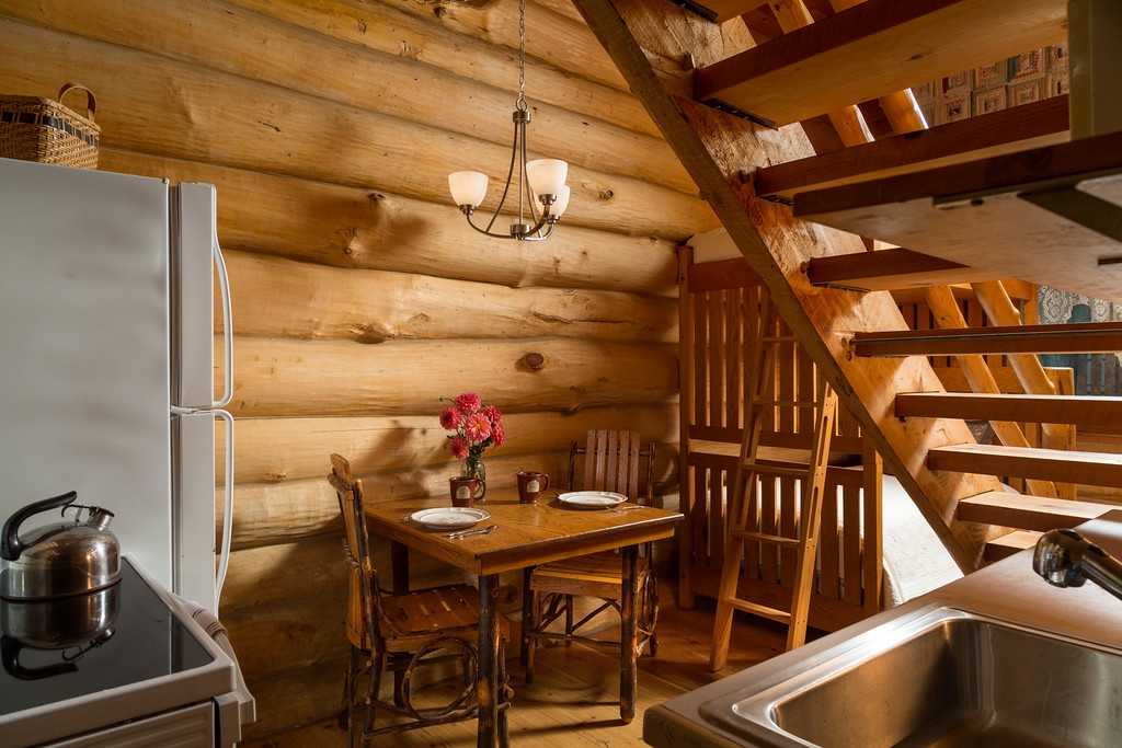 Kitchen area under open stairway to loft featuring a oak/hickory table with two chairs, stove, sink, and refrigerator/freezer.