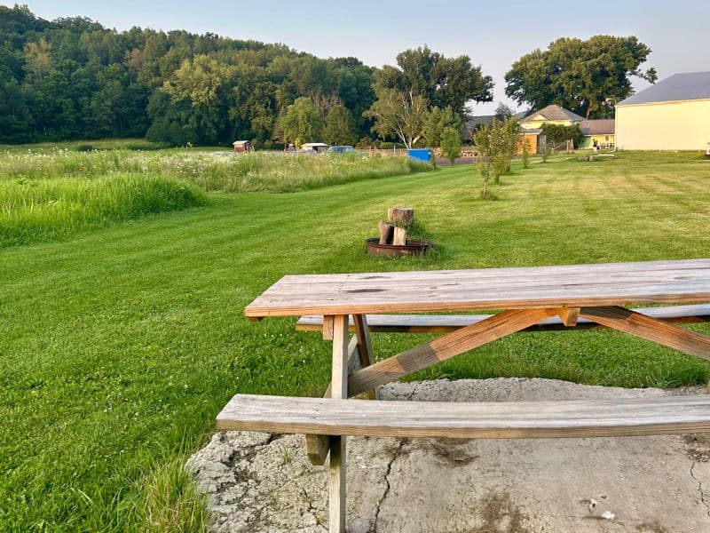 Campsite 1 with picnic table and bonfire area is less than 400 feet from White Barn where there is a bathroom with warm shower.