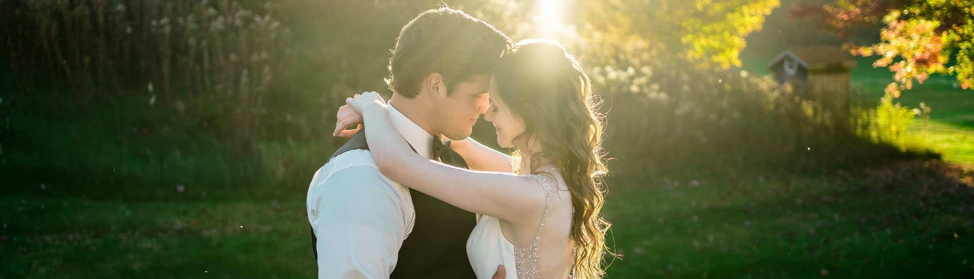 A couple dressed in wedding attire outside at sunset embracing