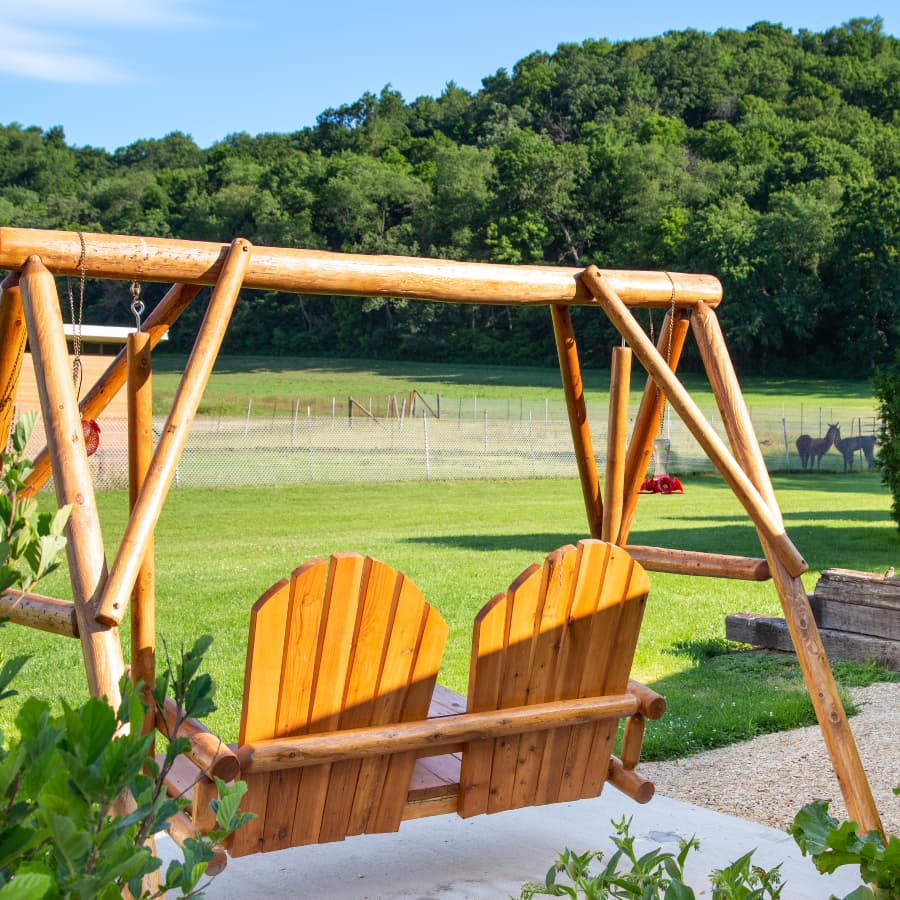 A peaceful outdoor space at Justin Trails Resort, featuring a wooden swing for two and a view of the surrounding countryside.