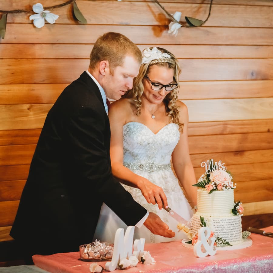 A couple dressed in wedding attire cutting their wedding cake