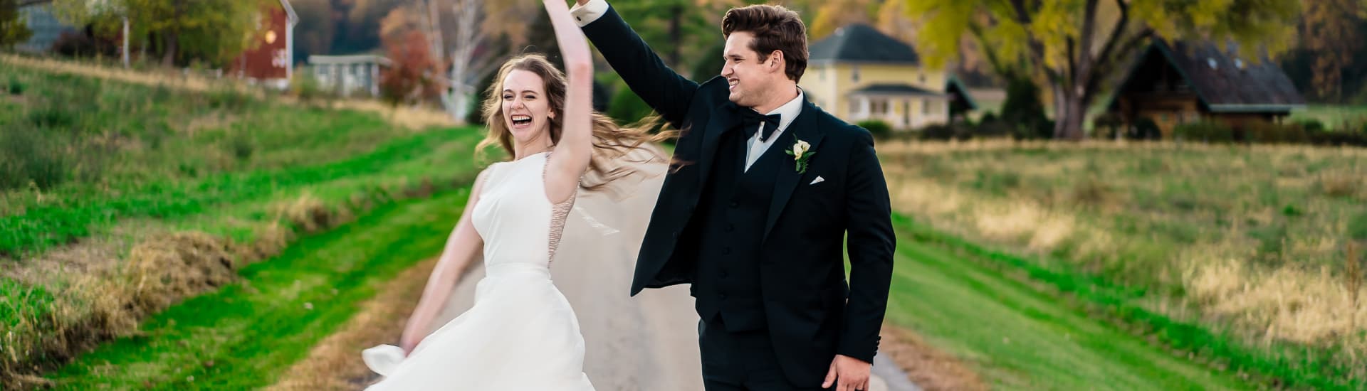 A bride and groom dressed in wedding attire outside spinning and laughing