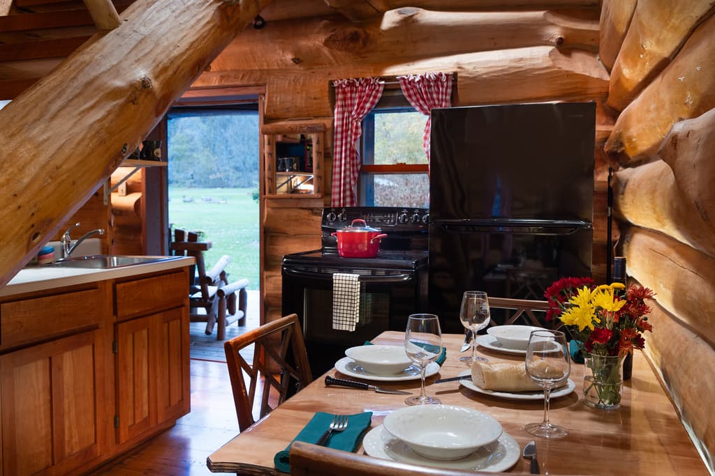 Kitchen in a log home with a table set with flowers and a loaf of fresh bread