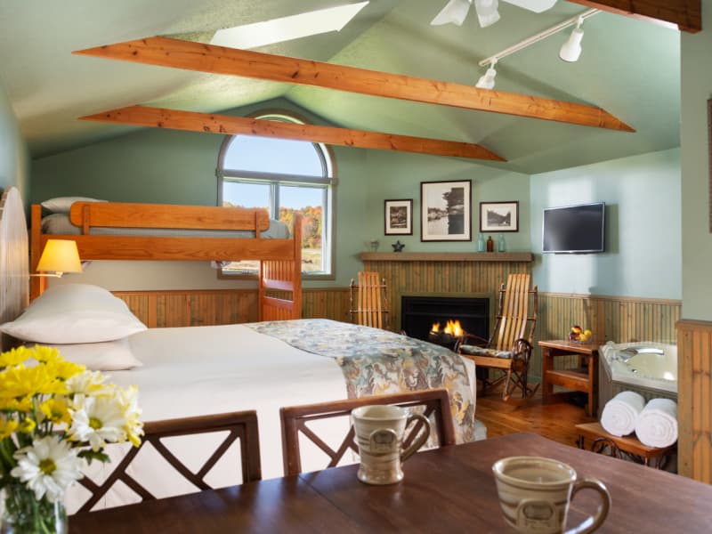 Interior of cottage with king size bed, dining area, corner fireplace and whirlpool tub.