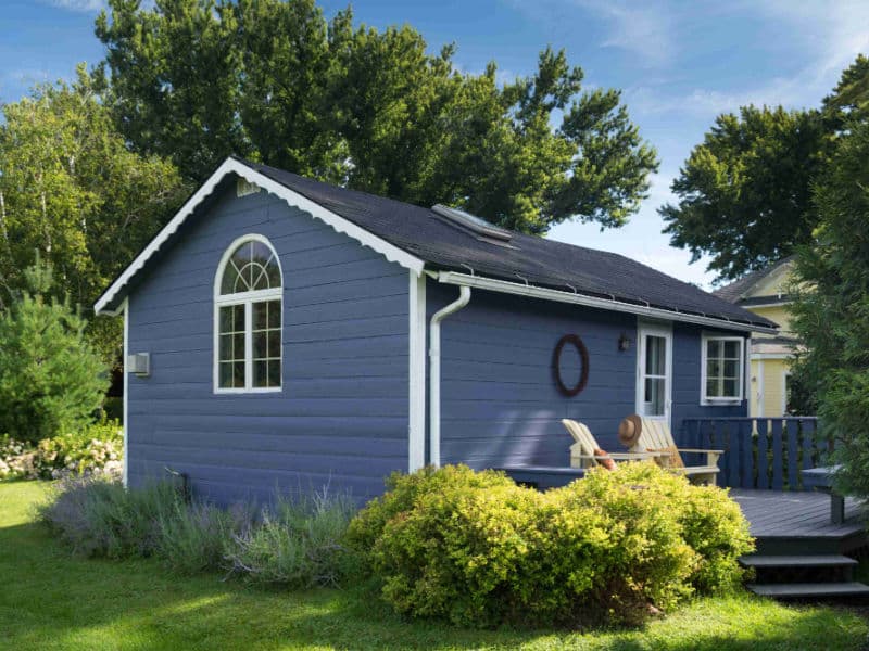 Exterior of a Wedgewood blue cottage with white trim, a wooden deck and private entrance.