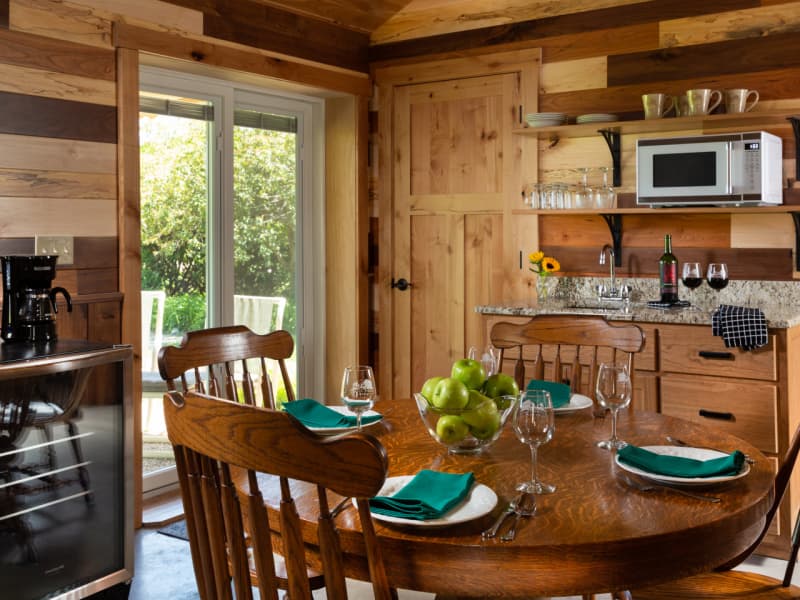 Kitchenette and round wooden table set for 4 inside Sunrise Cottage.