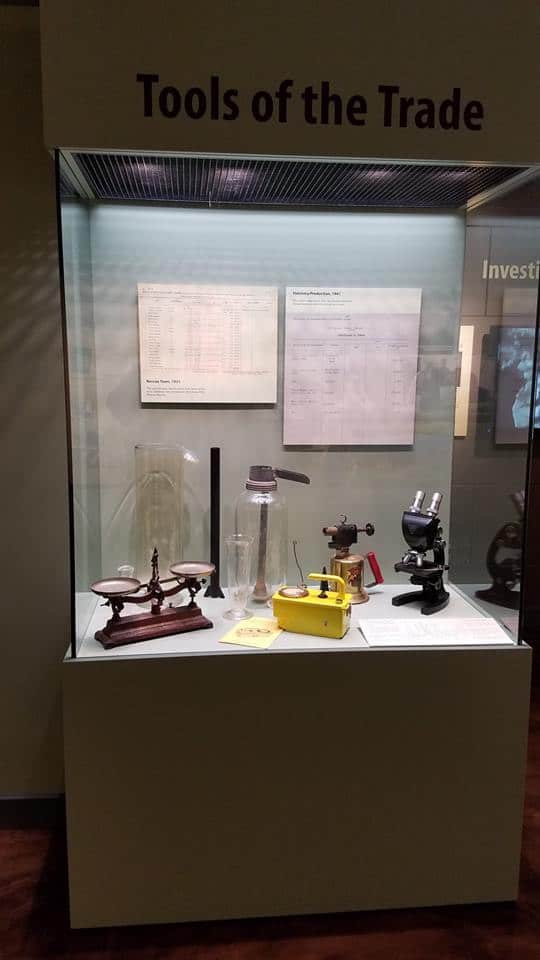 A display case featuring various historical scientific tools, including balances, beakers, and a microscope.