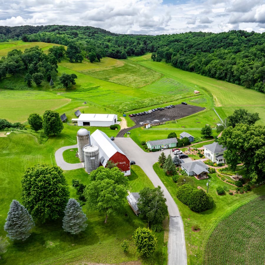 An aerial shot of Justin Trails resort with a large red barn, several buildings around the property, and miles of green grass and farmland, with lush trees around the perimeter