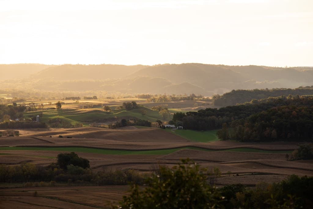 A scenic view of rolling hills and farmland bathed in golden sunlight.