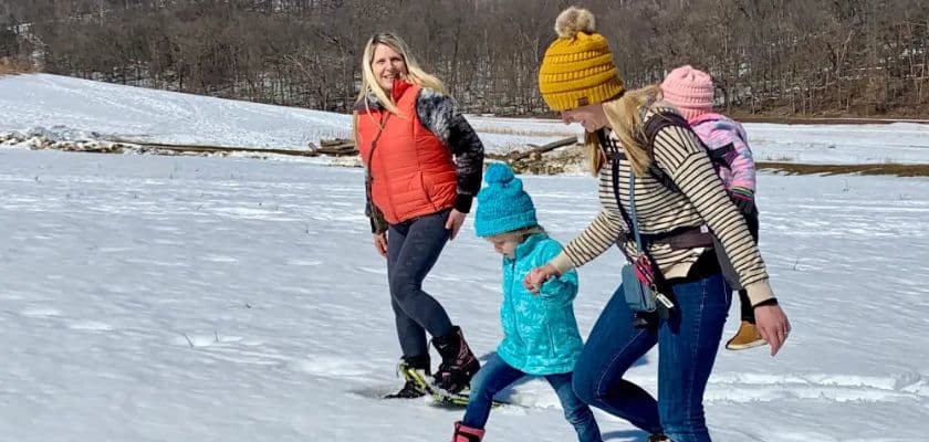 Two women and two children enjoy a snowy walk outdoors.
