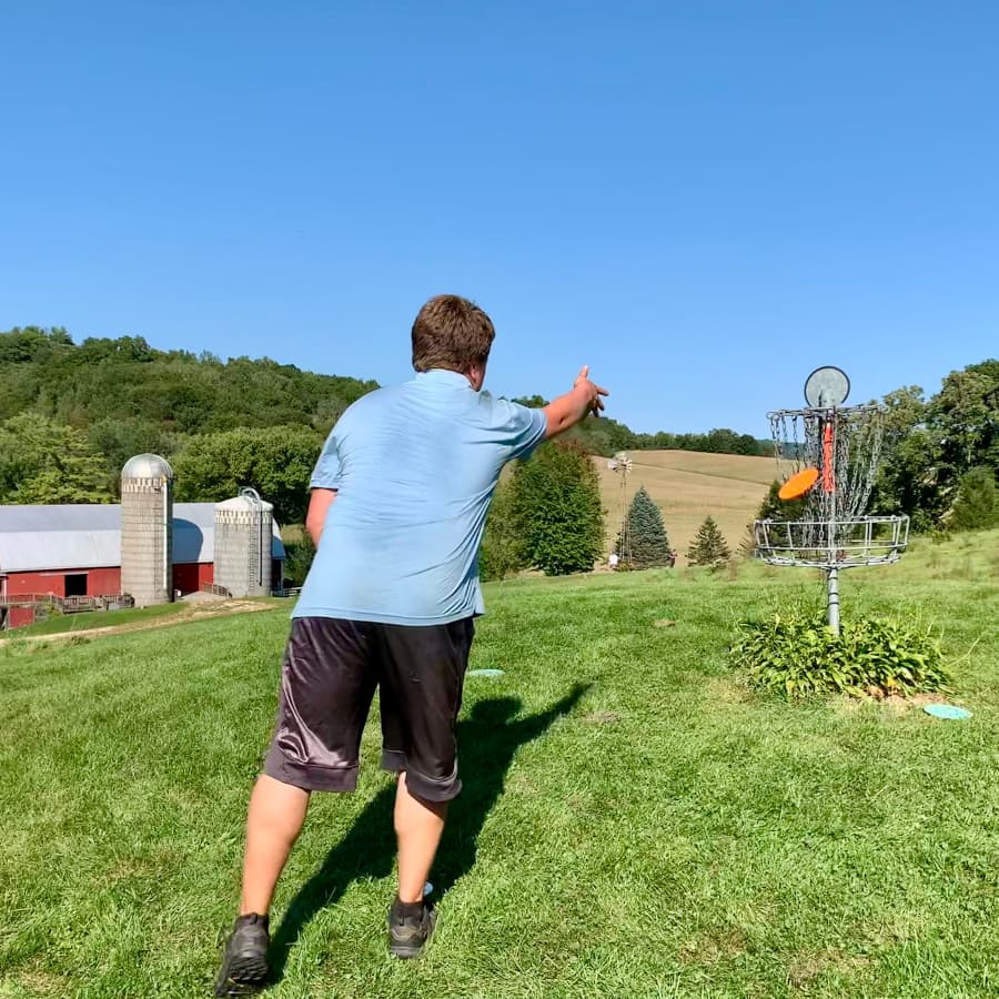 A man throwing a disc into a disc golf basket