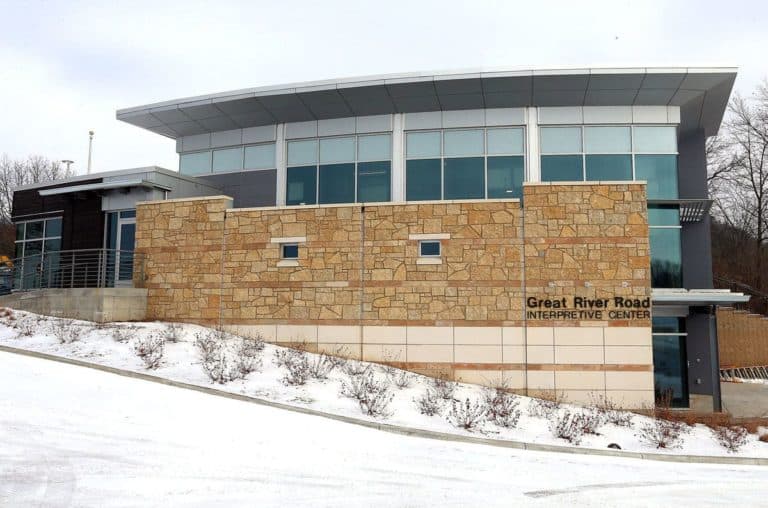 Modern stone and glass building of the Great River Road Interpretive Center in a snowy landscape.