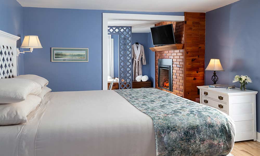 Cozy bedroom with a blue color scheme, a fireplace, and a TV.