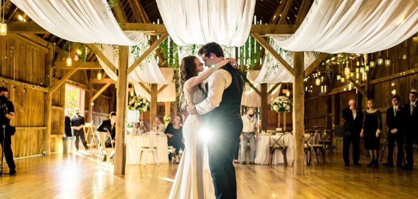 A couple dances romantically in a elegantly decorated barn for their wedding.