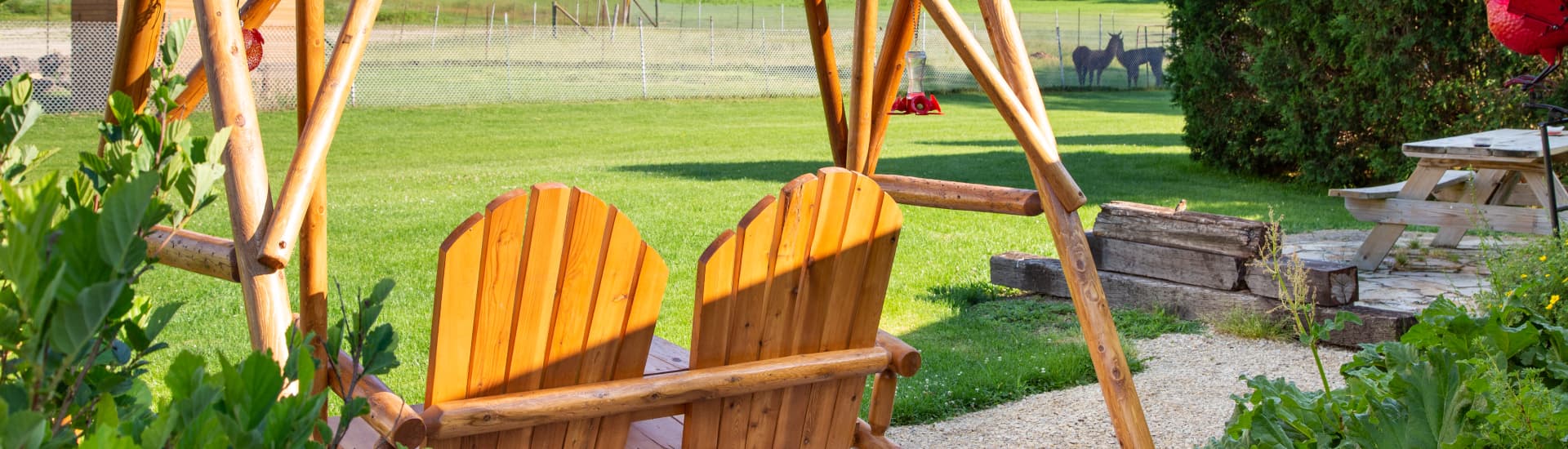 A wood porch swing for two overlooking green grass and farmland