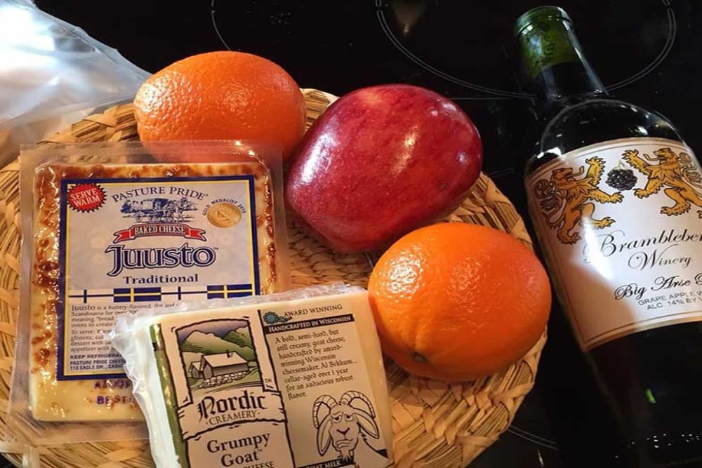A wicker basket with fresh fruit, some local fresh cheeses, and a bottle of wine